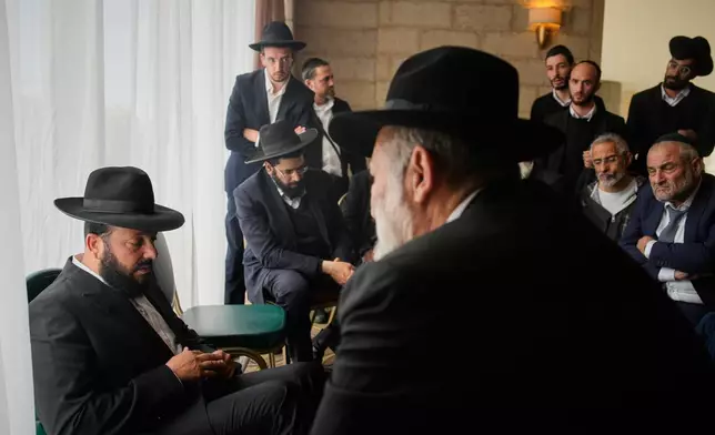 Friends and relatives comfort Yitzhak Biton, left, whose three children, Yaakov, Avigail and Sarah, were killed earlier this week when an Iranian missile struck their home in the city of Beit Shemesh, Jerusalem, Thursday, March 5, 2026. (AP Photo/Ohad Zwigenberg)