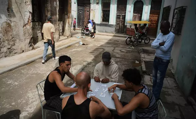 People play dominoes outside during a blackout in Havana, Tuesday, March 17, 2026. (AP Photo/Ramon Espinosa)