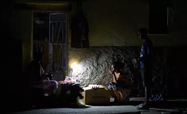 Street vendors chat during a blackout in Havana, Monday, March 16, 2026. (AP Photo/Ramon Espinosa)