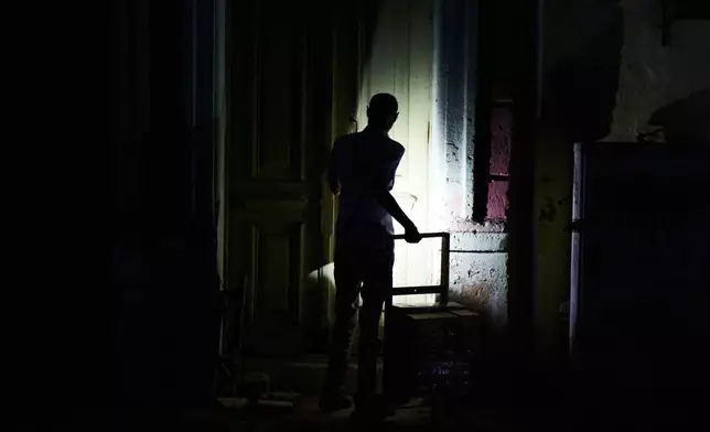 A man enters his building during a blackout in Havana, Monday, March 16, 2026. (AP Photo/Ramon Espinosa)