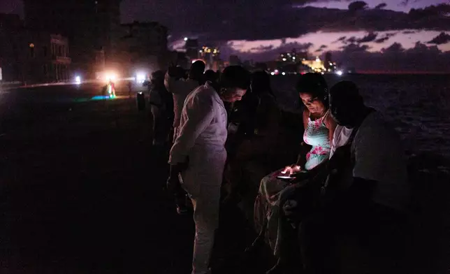 People spend the night in the dark on the Malecon during a blackout in Havana, Cuba, Saturday, March 21, 2026. (AP Photo/Ramon Espinosa)