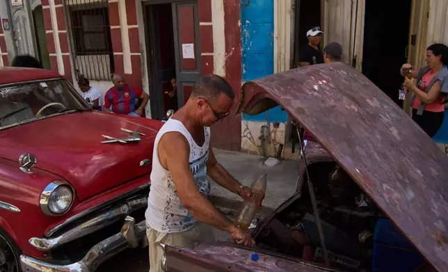 A man finishes putting fuel in his car's tank, located in the back of the car, during a blackout in Havana, Cuba, Monday, March 16, 2026. (AP Photo/Ramon Espinosa)