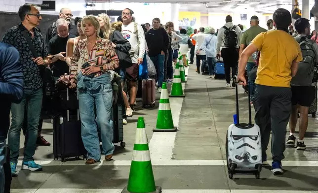 Airline passengers wait outside the terminal in the parking garage in long lines to get through the TSA security screening at William P. Hobby Airport in Houston, Sunday, March 8, 2026. (Brett Coomer/Houston Chronicle via AP)
