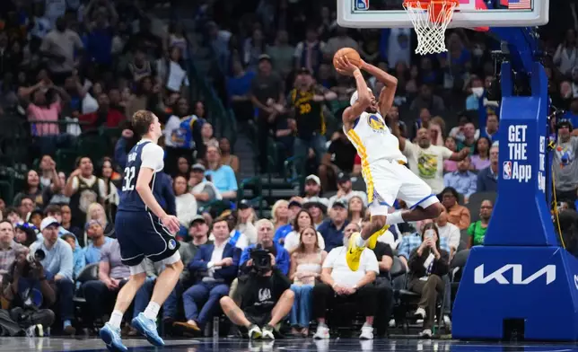 Golden State Warriors guard Moses Moody, right, reacts while suffering an injury as Dallas Mavericks forward Cooper Flagg (32) looks on during overtime of an NBA basketball game Monday, March 23, 2026, in Dallas. (AP Photo/Julio Cortez)