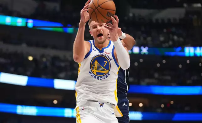 Golden State Warriors center Kristaps Porzingis (7) competes for a rebound against Dallas Mavericks guard Max Christie during the first half of an NBA basketball game Monday, March 23, 2026, in Dallas. (AP Photo/Julio Cortez)