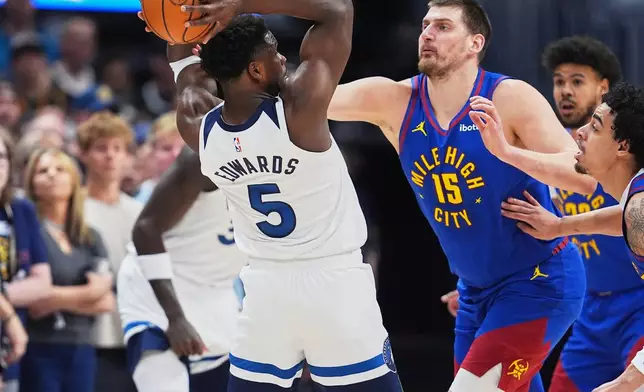 Minnesota Timberwolves guard Anthony Edwards, left, looks to pass the ball as Denver Nuggets center Nikola Jokić defends in the first half of an NBA basketball game, Sunday, March 1, 2026, in Denver. (AP Photo/David Zalubowski)