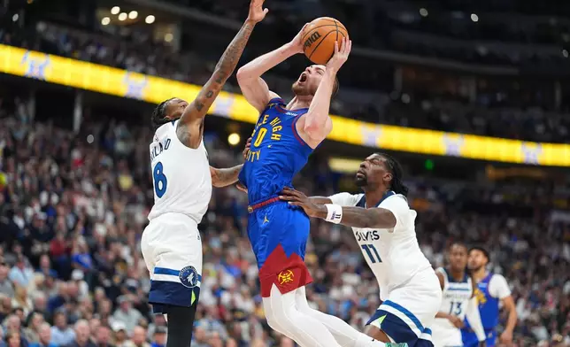 Denver Nuggets guard Christian Braun, center, drives to the basket between Minnesota Timberwolves guard Bones Hyland, left, and center Naz Reid (11) in the first half of an NBA basketball game Sunday, March 1, 2026, in Denver. (AP Photo/David Zalubowski)