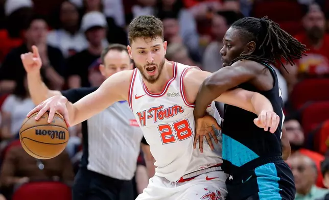 Houston Rockets center Alperen Sengun (28) drives into Portland Trail Blazers guard Jrue Holiday, right, during the first half of an NBA basketball game Friday March 6, 2026, in Houston. (AP Photo/Michael Wyke)