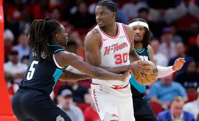 Portland Trail Blazers guard Jrue Holiday (5) reaches in as Houston Rockets center Clint Capela (30) looks to pass the ball during the first half of an NBA basketball game Friday March 6, 2026, in Houston. (AP Photo/Michael Wyke)