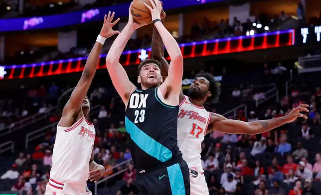 Portland Trail Blazers center Donovan Clingan (23) puts up a shot between Houston Rockets guard Amen Thompson, left, and forward Tari Eason (17) during the first half of an NBA basketball game Friday March 6, 2026, in Houston. (AP Photo/Michael Wyke)