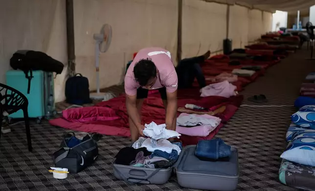 A stranded Indian traveler takes his clothes out of his suitcase after arriving at a farmhouse owned by an Indian businessman, now converted into a shelter in Ajman, near Dubai, United Arab Emirates, Saturday, March 7, 2026. (AP Photo/Altaf Qadri)