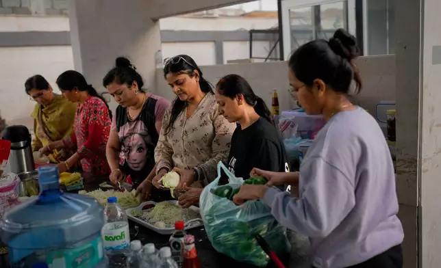 Stranded Indian travelers help prepare food at a farmhouse owned by an Indian businessman, now converted into a shelter in Ajman, near Dubai, United Arab Emirates, Saturday, March 7, 2026. (AP Photo/Altaf Qadri)