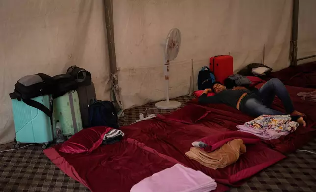 A stranded Indian traveler sleeps inside a tent at a farmhouse owned by an Indian businessman, now converted into a shelter in Ajman, near Dubai, United Arab Emirates, Saturday, March 7, 2026. (AP Photo/Altaf Qadri)