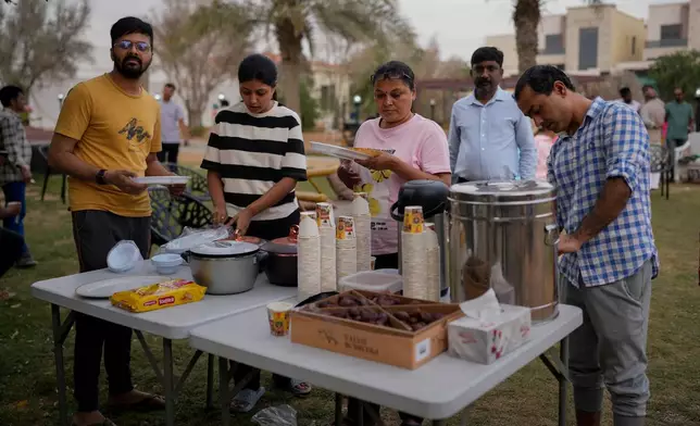 Stranded Indian travelers share evening tea and snacks at a farmhouse owned by an Indian businessman, now converted into a shelter in Ajman, near Dubai, United Arab Emirates, Saturday, March 7, 2026. (AP Photo/Altaf Qadri)