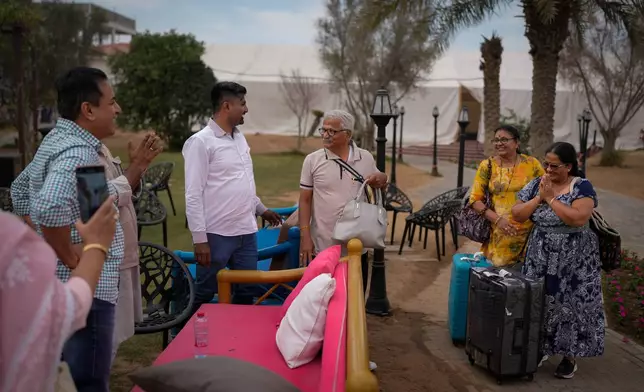 Stranded Indian travelers show their gratitude to Dhiraj Jain, an Indian businessman second from left in a white shirt, at his farmhouse, now converted into a shelter in Ajman, near Dubai, United Arab Emirates, Saturday, March 7, 2026. (AP Photo/Altaf Qadri)