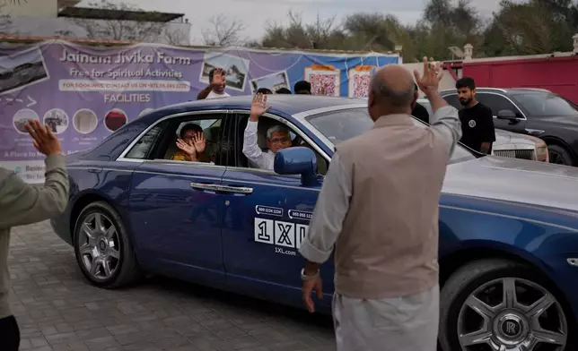 Stranded foreign travelers wave to others as they depart from the farmhouse owned by an Indian businessman, now converted into a shelter, in Ajman, near Dubai, United Arab Emirates, Saturday, March 7, 2026. (AP Photo/Altaf Qadri)