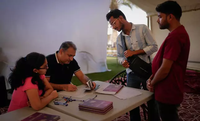 Stranded Indian travelers Mohammad Nahid, second right, and Amit Kumar, right, register their names at a farmhouse owned by an Indian businessman, now converted into a shelter in Ajman, near Dubai, United Arab Emirates, Saturday, March 7, 2026. (AP Photo/Altaf Qadri)