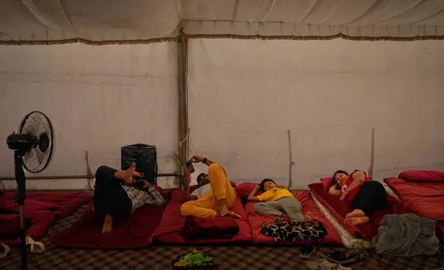 Stranded Indian travelers lie down inside a tent at a farmhouse owned by an Indian businessman, now converted into a shelter in Ajman, near Dubai, United Arab Emirates, Saturday, March 7, 2026. (AP Photo/Altaf Qadri)
