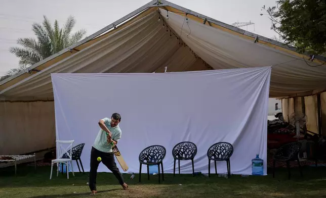 A stranded Indian traveler plays cricket at a farmhouse owned by an Indian businessman, now converted into a shelter in Ajman, near Dubai, United Arab Emirates, Saturday, March 7, 2026. (AP Photo/Altaf Qadri)