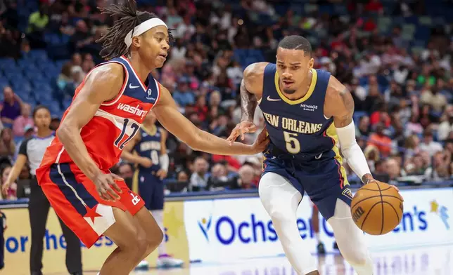 New Orleans Pelicans guard Dejounte Murray (5) tries to drive past Washington Wizards guard Tre Johnson (12) in the first half of an NBA basketball game in New Orleans, Sunday, March 8, 2026. (AP Photo/Peter Forest)