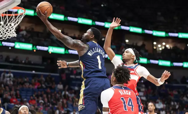 New Orleans Pelicans forward Zion Williamson (1) drives between Washington Wizards forward Leaky Black (14) and guard Bilal Coulibaly, right, for a layup in the first half of an NBA basketball game in New Orleans, Sunday, March 8, 2026. (AP Photo/Peter Forest)