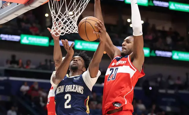 New Orleans Pelicans forward Herb Jones (2) attempts a reverse layup against Washington Wizards center Alex Sarr (20) in the first half of an NBA basketball game in New Orleans, Sunday, March 8, 2026. (AP Photo/Peter Forest)