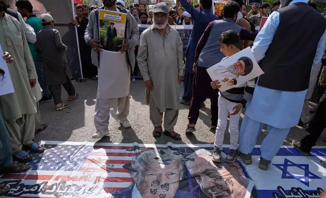 Shiite Muslims walk over the representation of U.S. and Israeli flags with pictures of President Donald Trump and Prime Minister Benjamin Netanyahu during a rally to condemn the killing of Iranian Supreme Leader Ayatollah Ali Khamenei and against the Israeli strikes on Iran, in Islamabad, Pakistan, Friday, March 6, 2026. (AP Photo/Anjum Naveed)