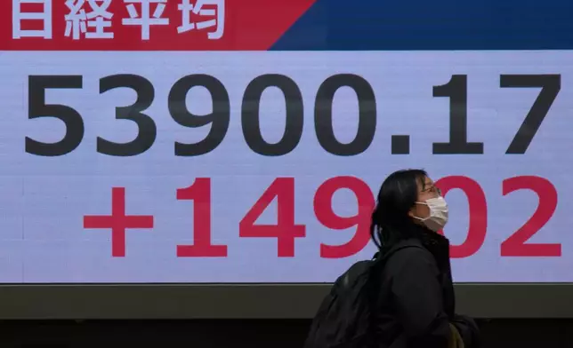 A person walks near a stock price monitor showing Nikkei index at a security company Tuesday, March 17, 2026, in Tokyo. (AP Photo/Eugene Hoshiko)