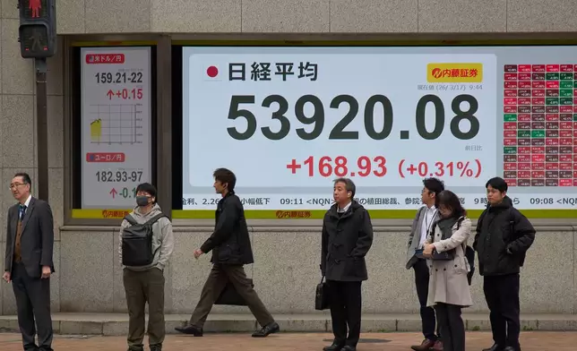 People stand in front of a stock price monitor showing Nikkei index at a security company Tuesday, March 17, 2026, in Tokyo. (AP Photo/Eugene Hoshiko)