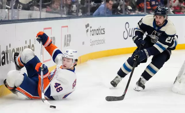 New York Islanders defenseman Matthew Schaefer (48) falls in front of Columbus Blue Jackets center Sean Monahan (23) as he brings the puck behind the net in the second period of an NHL hockey game in Columbus, Ohio, Saturday, Feb. 28, 2026. (AP Photo/Sue Ogrocki)