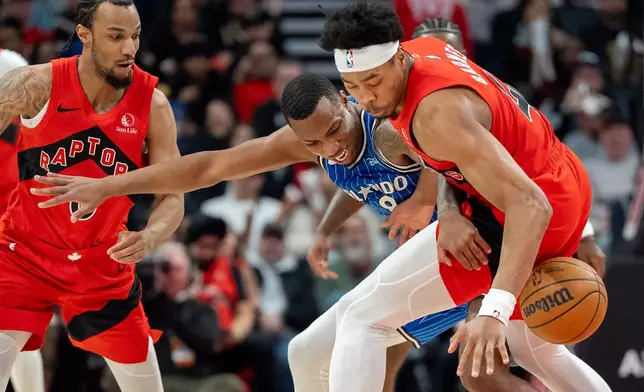 Toronto Raptors forward Scottie Barnes (right) strips the ball from Orlando Magic forward Jamal Cain (8) as Raptors guard A.J. Lawson (0) helps during first half NBA action in Toronto on Sunday, March 29, 2026. (Frank Gunn/The Canadian Press via AP)