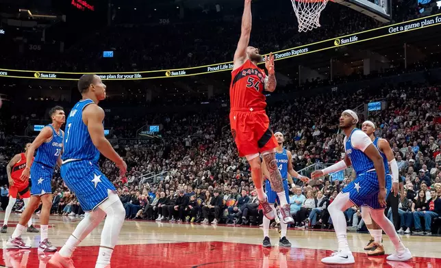 Toronto Raptors forward Sandro Mamukelashvili (54) scores between the Orlando Magic defense during first half NBA action in Toronto on Sunday, March 29, 2026. (Frank Gunn/The Canadian Press via AP)