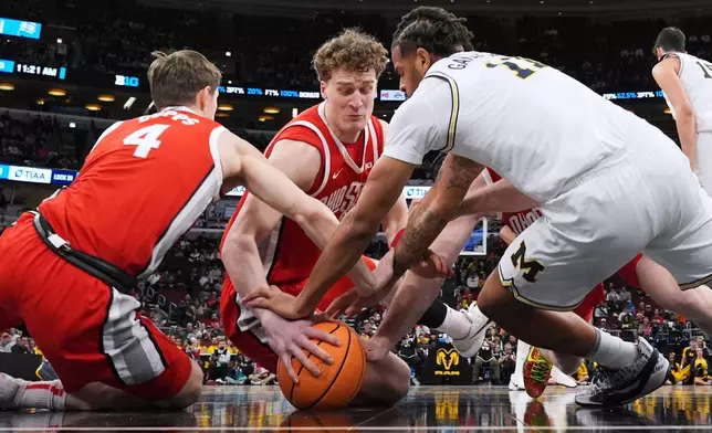 Ohio State center Christoph Tilly, center, battles for a loose ball against guard Gabe Cupps, left, and Michigan guard Roddy Gayle Jr. during the first half of an NCAA college basketball game in the quarterfinals of the Big 10 Conference tournament, Friday, March 13, 2026, in Chicago. (AP Photo/Nam Y. Huh)