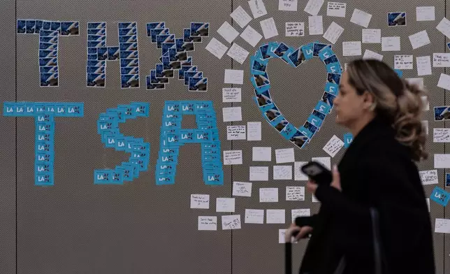 A traveler walks past a display of thank-you notes for TSA agents at Los Angeles International Airport, Friday, March 27, 2026, in Los Angeles. (AP Photo/Jae C. Hong)