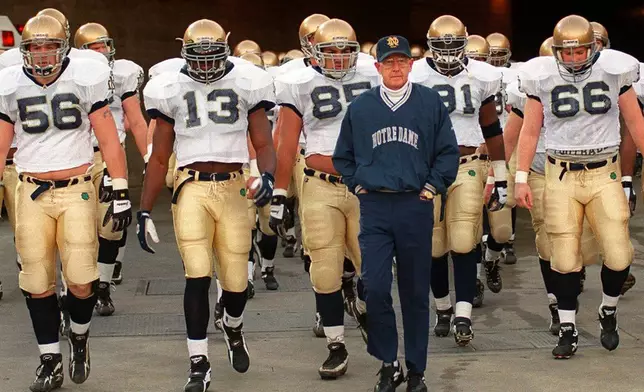 FILE - Notre Dame's head coach Lou Holtz and the Fighting Irish walk onto the field of the Los Angeles Coliseum to warm up for an NCAA college football game against Southern California Saturday, Nov. 30, 1996 in Los Angeles. (AP Photo/Kevork Djansezian, File)