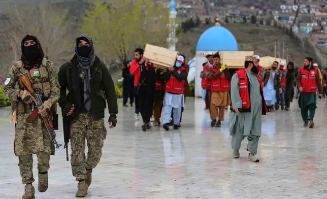 Taliban security personnel guard as people carry the remains of victims of a Monday airstrike on a drug rehabilitation hospital, ahead of the burials Wednesday, March 18, 2026, Kabul, Afghanistan. (AP Photo/Siddiqullah Alizai)