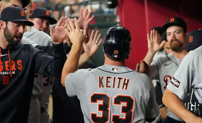 Detroit Tigers' Colt Keith (33) gets high fives from teammates after scoring during the seventh inning of an opening-day baseball game against the Arizona Diamondbacks Monday, March 30, 2026, in Phoenix. (AP Photo/Darryl Webb)