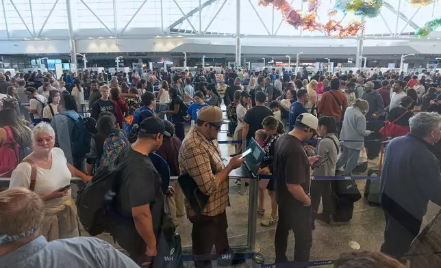 Passengers wait in a security checkpoint line at George Bush Intercontinental Airport Wednesday, March 25, 2026, in Houston. (AP Photo/David J. Phillip)