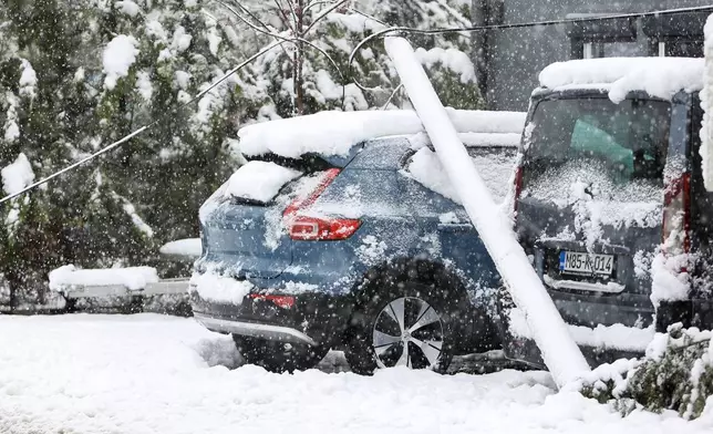 A telephone pole lies on a car during heavy snowfall in Bihac, Bosnia, Friday, March 27, 2026. (AP Photo/Edvin Zulic)