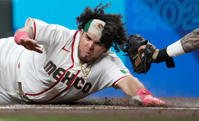Mexico's Jonathan Aranda scores ahead of a tag by Brazil catcher Gabriel Carmo during the first inning of a World Baseball Classic game, Sunday, March 8, 2026, in Houston. (AP Photo/Ashley Landis)