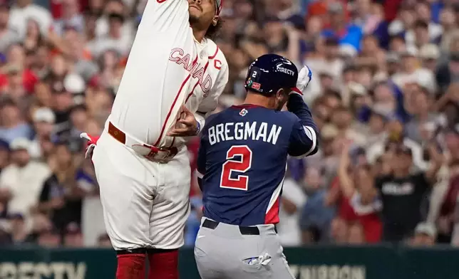 United States third baseman Alex Bregman (2) is safe at first base as Canada first baseman Josh Naylor, left, reaches for a wild throw during the third inning of a World Baseball Classic quarterfinal game, Friday, March 13, 2026, in Houston. (AP Photo/David J. Phillip)