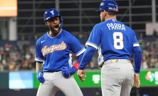 Venezuela Maikel Garcia reacts to first base coach Gerardo Parra (8) after getting on the base during the seventh inning of a World Baseball Classic semifinal game against Italy, Monday, March 16, 2026, in Miami. (AP Photo/Rebecca Blackwell)