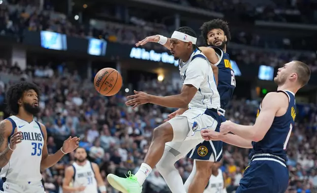 Dallas Mavericks guard Brandon Williams, center right, passes the ball to Dallas Mavericks forward Marvin Bagley III, left, while driving the lane past Denver Nuggets guards Jamal Murray, back right, and Christian Braun in the first half of an NBA basketball game Wednesday, March 25, 2026, in Denver. (AP Photo/David Zalubowski)