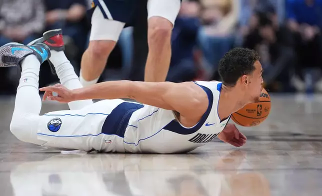 Dallas Mavericks forward Dwight Powell dives after a loose ball in the first half of an NBA basketball game against the Denver Nuggets Wednesday, March 25, 2026, in Denver. (AP Photo/David Zalubowski)