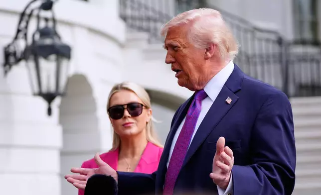 President Donald Trump speaks with reporters as he walks to depart on Marine One from the South Lawn of the White House, Wednesday, March 11, 2026, in Washington, as White House press secretary Karoline Leavitt, looks on. (AP Photo/Alex Brandon)