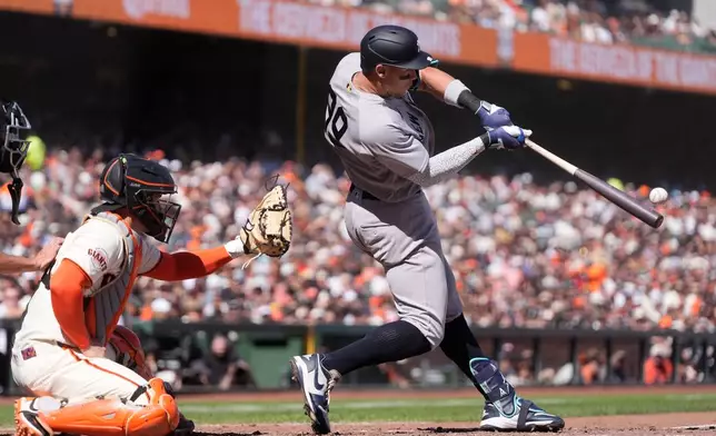 New York Yankees' Aaron Judge, right, hits a two-run home run next to San Francisco Giants catcher Patrick Bailey during the sixth inning of a baseball game in San Francisco, Friday, March 27, 2026. (AP Photo/Jeff Chiu)