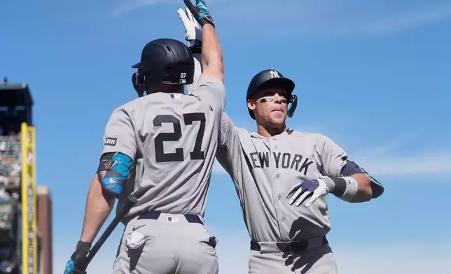 New York Yankees' Aaron Judge, right, is congratulated by Giancarlo Stanton (27) after hitting a two-run home run that also scored Paul Goldschmidt during the sixth inning of a baseball game against the San Francisco Giants in San Francisco, Friday, March 27, 2026. (AP Photo/Jeff Chiu)