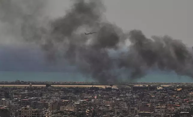 A Middle East Airlines plane takes off from Rafik Hariri International Airport as smoke rises from the site of an Israeli airstrike in Dahiyeh, Beirut's southern suburbs, Lebanon, Tuesday, March 17, 2026. (AP Photo/Hassan Ammar)