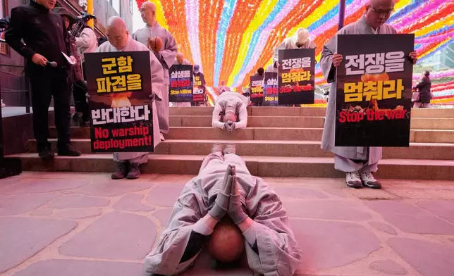 South Korean Buddhist monks and members of civic groups bow and prostrate themselves on the road as they march towards the U.S. Embassy in Seoul, South Korea, to protest against President Donald Trump asking multiple countries to send warships to reopen the Strait of Hormuz, Tuesday, March 17, 2026. (AP Photo/Ahn Young-joon)
