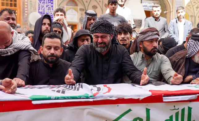 Relatives pray near the coffin of an Iranian-backed Popular Mobilization Forces fighter killed in recent airstrikes on Qaim, Tuesday, March 17, 2026. in Najaf, Iraq. (AP Photo/Anmar Khalil)